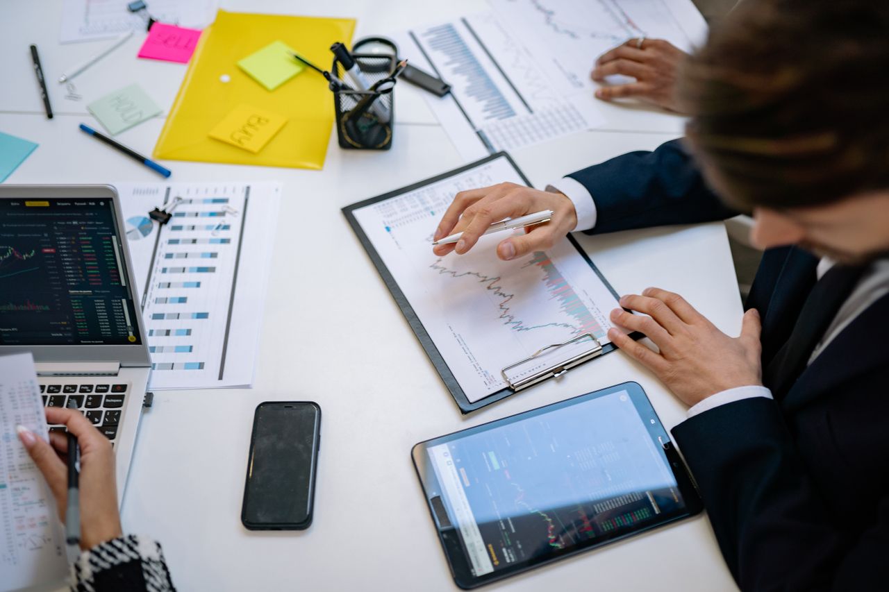 our-story Équipe consultant des graphiques financiers et des données numériques sur des tablettes, dans un environnement de bureau.